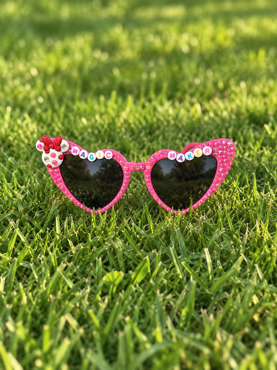 Pink heart-shaped rhinestone sunglasses with beaded 'Magic Maker' lettering