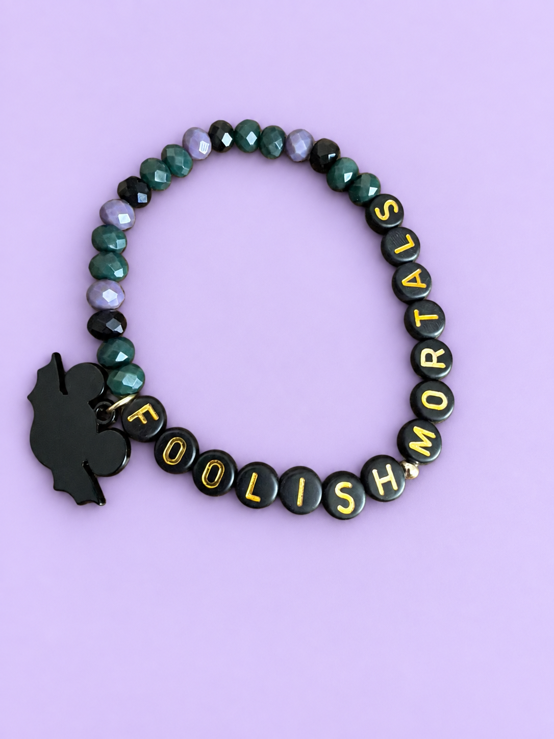 Green, lilac, and black beaded bracelet with gold lettering and a black charm
